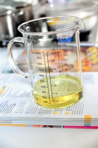 A glass measuring cup filled with yellow liquid, showing measurements in milliliters (ml) and pints.