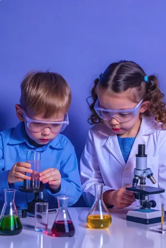 Children practicing Science Lessons 101 by performing a chemistry experiment with a microscope and beakers.