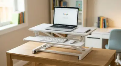 A clean, minimalist white riser desk on a wooden table featuring a laptop and a notepad.
