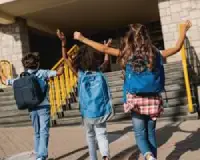 Group of happy children wearing the best school backpacks for kids while walking to school together.